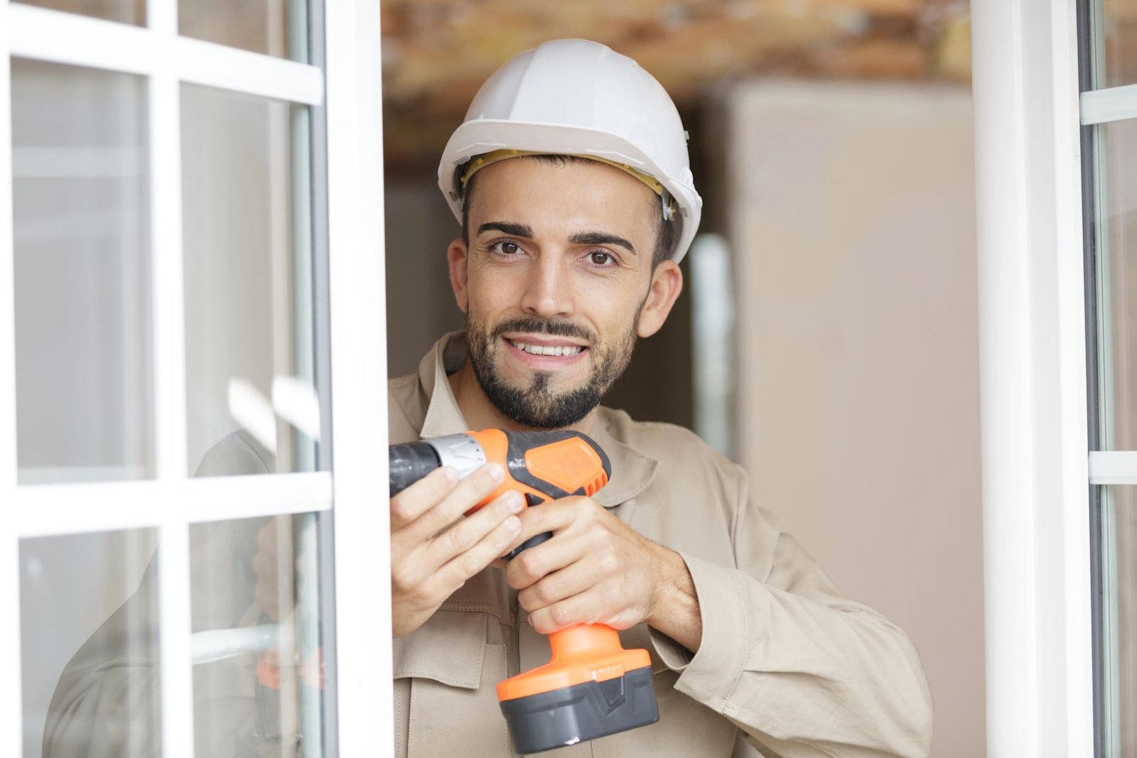 Handyman holding a cordless drill at a window frame (demo image)